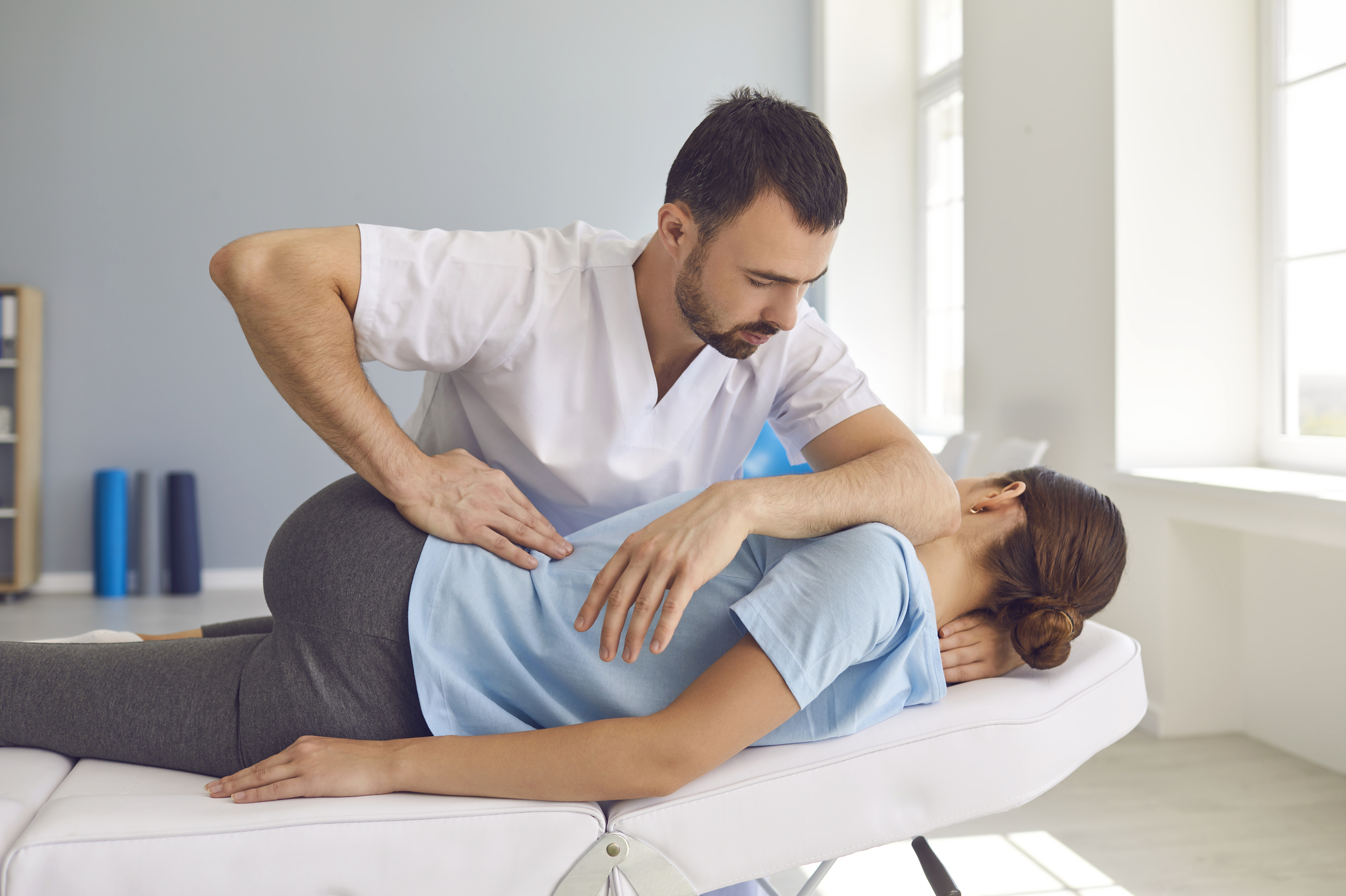 What You Shouldn’t Believe About Chiropractic Care - Man doctor chiropractor or osteopath fixing lying womans back in manual therapy clinic
